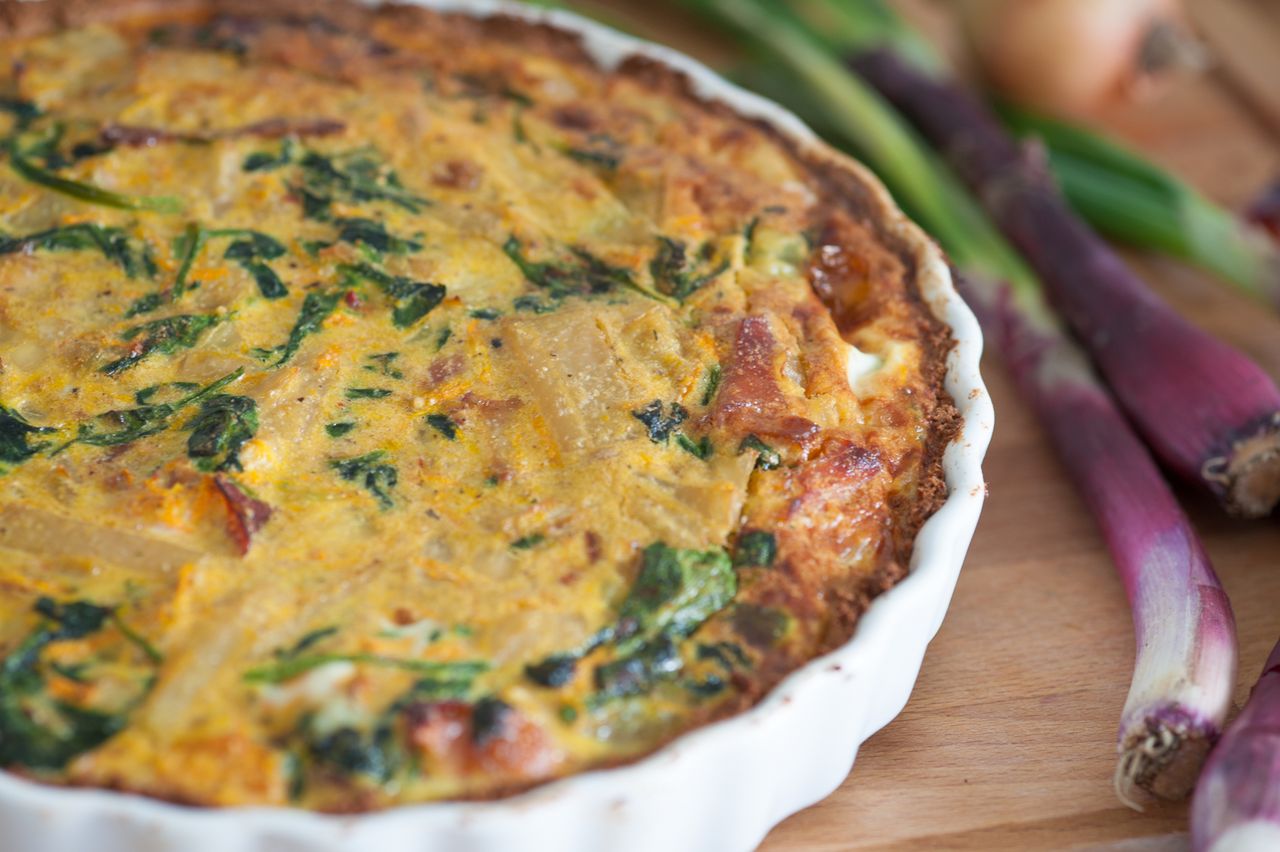 about-us Delicious homemade quiche with fresh red onions and spinach, perfect for a tasty meal.